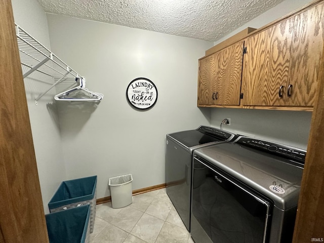 laundry room with washer and dryer, light tile patterned floors, cabinets, and a textured ceiling