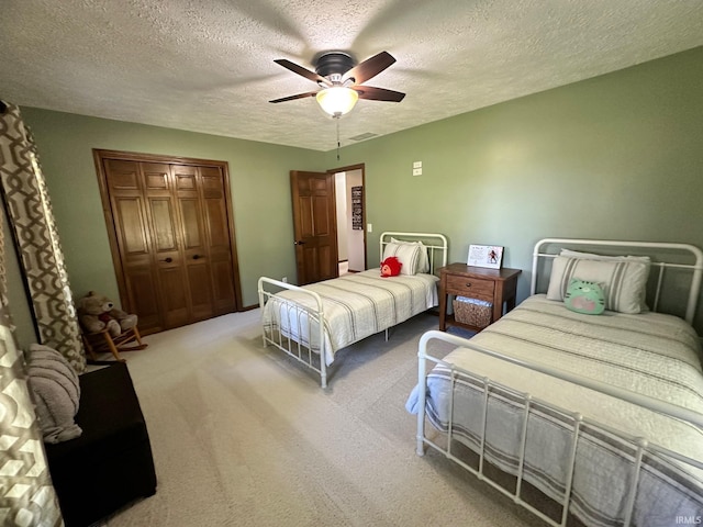 bedroom featuring carpet, ceiling fan, a textured ceiling, and a closet