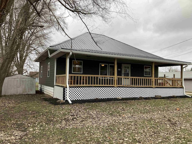 rear view of property with a storage unit and a porch