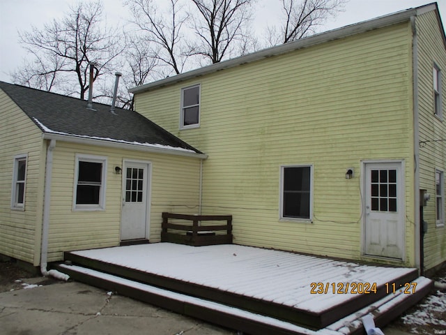 snow covered rear of property with a deck