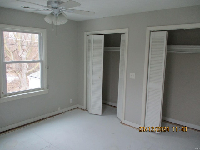 unfurnished bedroom with multiple closets and ceiling fan