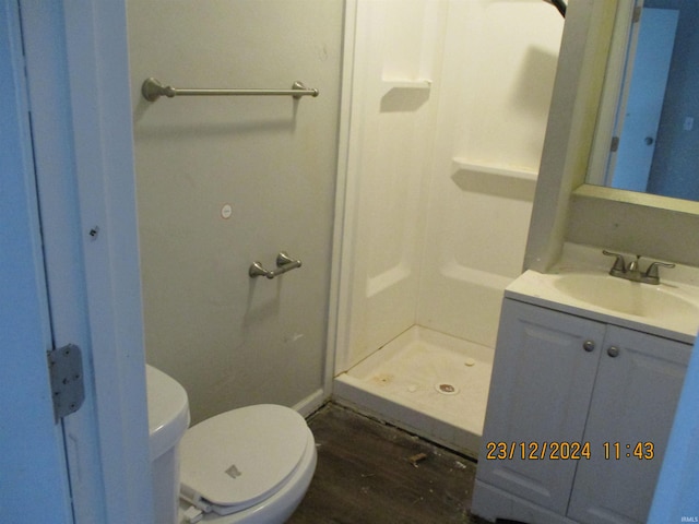 bathroom with hardwood / wood-style flooring, a shower, vanity, and toilet