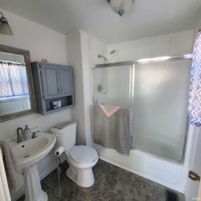 full bathroom featuring toilet, shower / bath combination with glass door, and sink