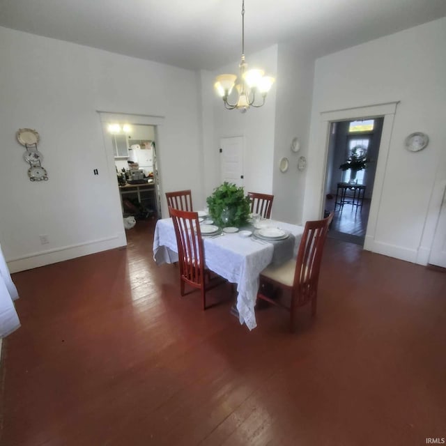 dining area with dark hardwood / wood-style flooring and a notable chandelier