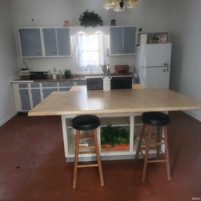 kitchen featuring white fridge, sink, and a breakfast bar area