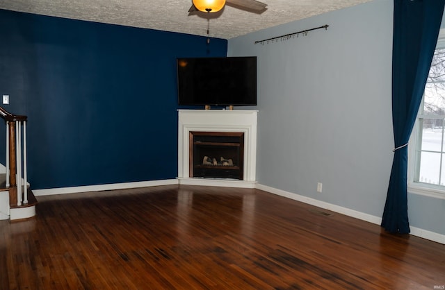 unfurnished living room featuring ceiling fan, a textured ceiling, and dark hardwood / wood-style flooring