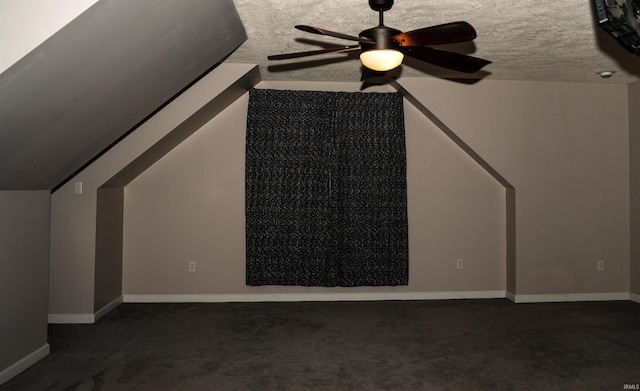 additional living space with ceiling fan, vaulted ceiling, a textured ceiling, and dark colored carpet