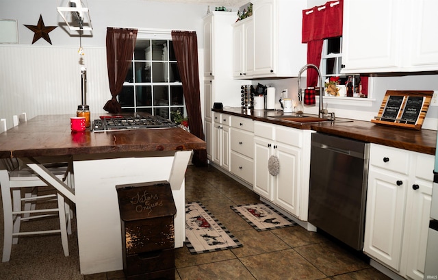 kitchen with sink, stainless steel appliances, wood counters, white cabinets, and dark tile patterned flooring