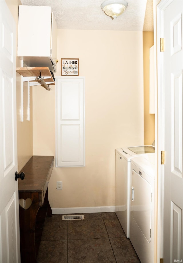 laundry area featuring washing machine and dryer, dark tile patterned flooring, and a textured ceiling