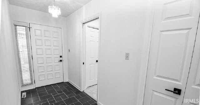 foyer entrance with a textured ceiling and a chandelier