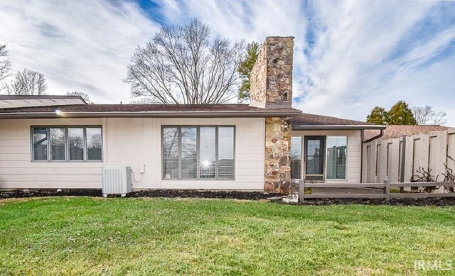 rear view of house with a yard and cooling unit