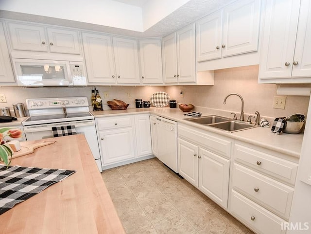 kitchen with white appliances, white cabinetry, and sink