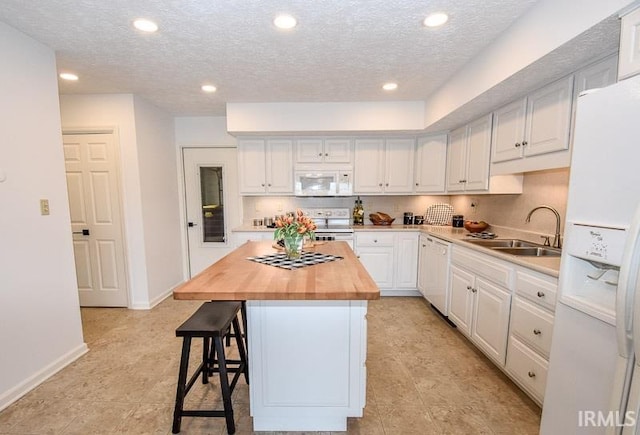 kitchen with sink, a kitchen island, wooden counters, white appliances, and white cabinets