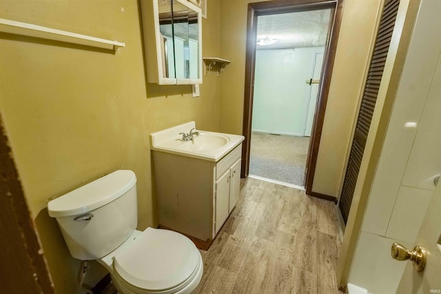 bathroom with hardwood / wood-style floors, vanity, and toilet