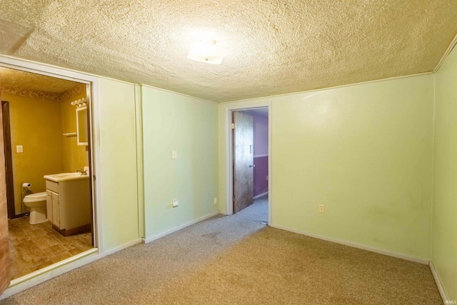 unfurnished room with carpet flooring, a textured ceiling, and sink