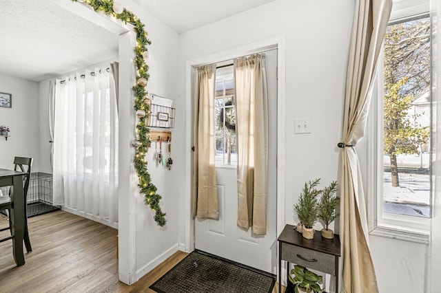 doorway to outside with light hardwood / wood-style floors and a textured ceiling