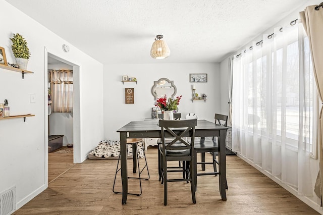 dining area featuring light wood-type flooring and a textured ceiling