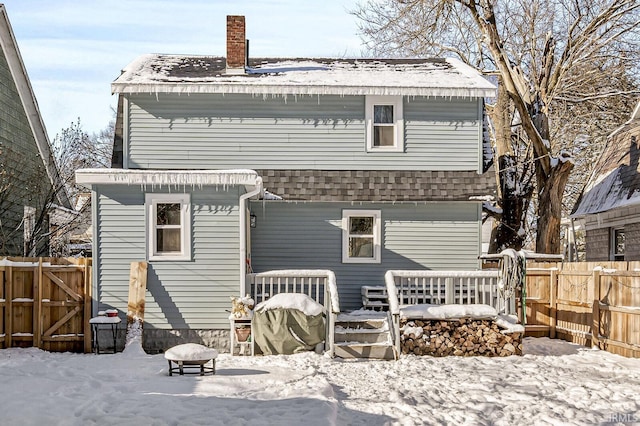 snow covered back of property with an outdoor fire pit