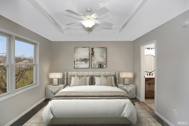 bedroom featuring a raised ceiling, connected bathroom, and ceiling fan