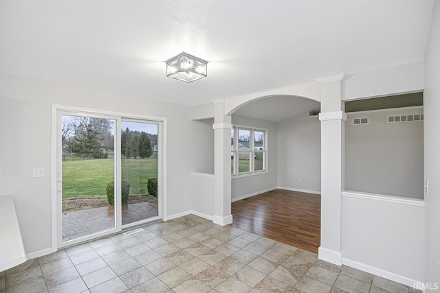 unfurnished room featuring decorative columns, plenty of natural light, and light tile patterned flooring