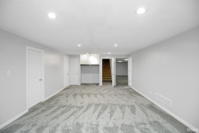 basement with a textured ceiling and light colored carpet