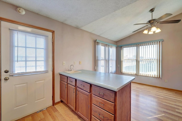 kitchen featuring kitchen peninsula, ceiling fan, vaulted ceiling, and light wood-type flooring