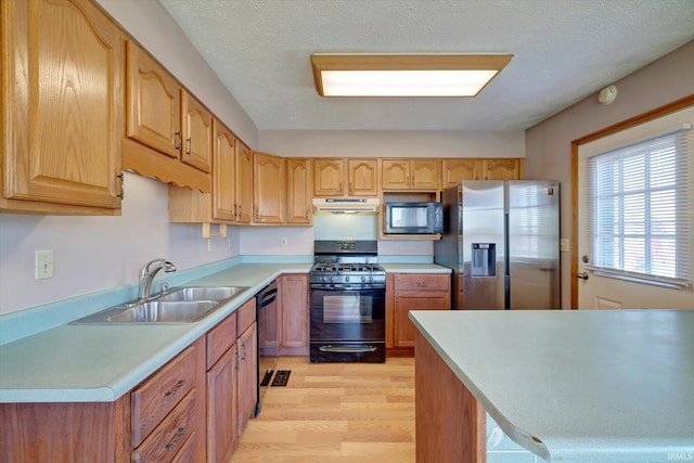 kitchen with sink, black appliances, a textured ceiling, and light wood-type flooring