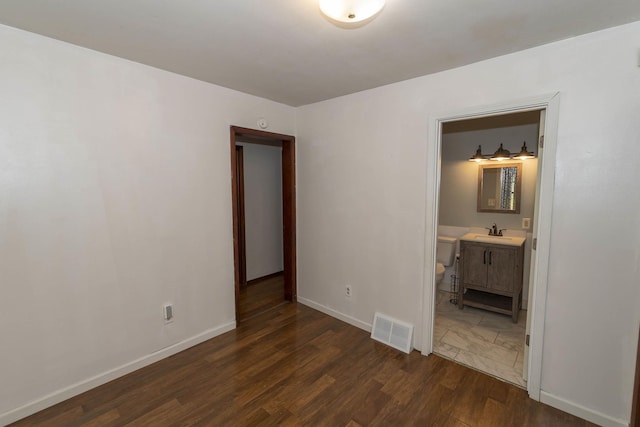 unfurnished bedroom with dark hardwood / wood-style flooring, sink, and connected bathroom