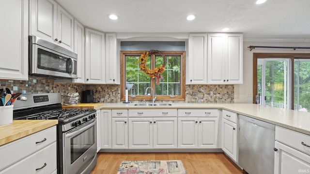 kitchen featuring decorative backsplash, appliances with stainless steel finishes, sink, light hardwood / wood-style flooring, and white cabinetry