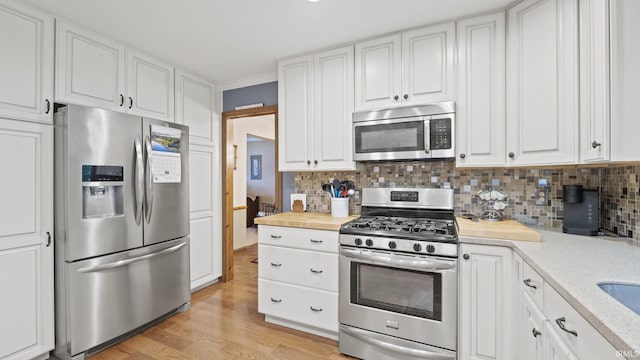 kitchen featuring wood counters, white cabinets, decorative backsplash, appliances with stainless steel finishes, and light hardwood / wood-style floors