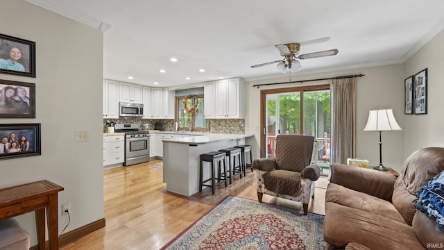 living room featuring crown molding, sink, ceiling fan, and light hardwood / wood-style floors