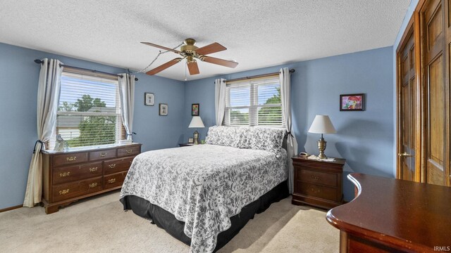 bedroom featuring a textured ceiling, ceiling fan, light carpet, and a closet