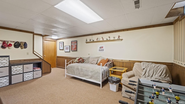 bedroom featuring ornamental molding, light colored carpet, a drop ceiling, and wooden walls