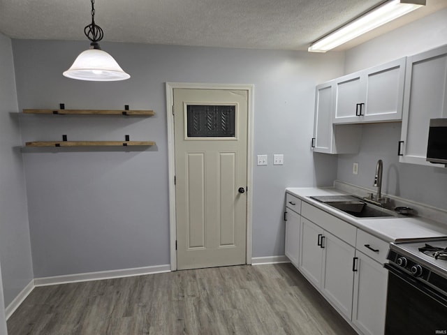 kitchen featuring white cabinets, a textured ceiling, decorative light fixtures, and sink