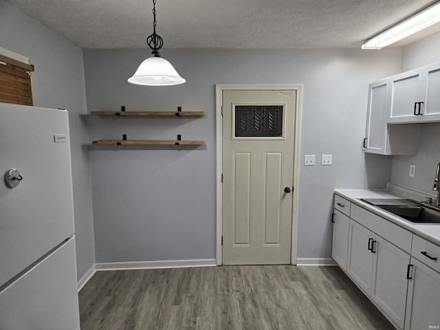 kitchen with white cabinets, pendant lighting, white fridge, and sink