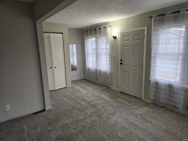 carpeted entrance foyer featuring a textured ceiling