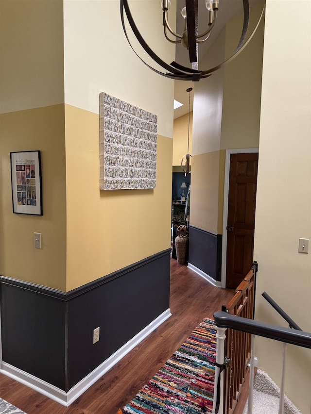 hall with a chandelier, dark hardwood / wood-style floors, and lofted ceiling