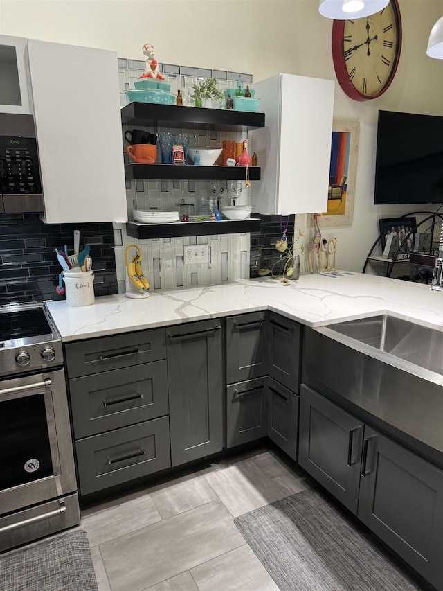 kitchen with appliances with stainless steel finishes, gray cabinets, and light stone counters