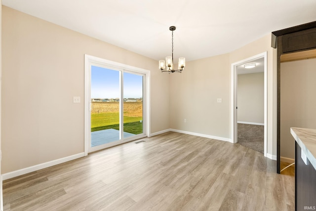 unfurnished dining area featuring light hardwood / wood-style flooring and a notable chandelier