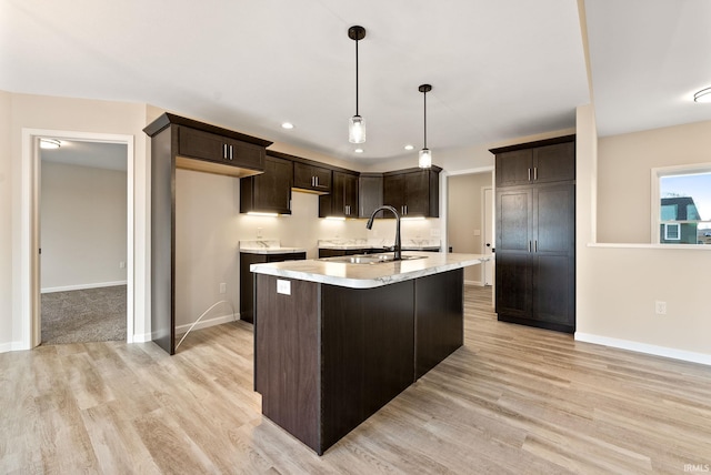 kitchen featuring dark brown cabinetry, sink, and light hardwood / wood-style flooring