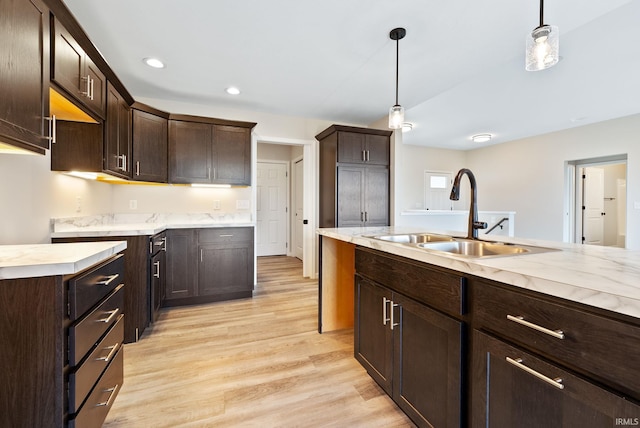 kitchen featuring sink, pendant lighting, dark brown cabinets, and light wood-type flooring