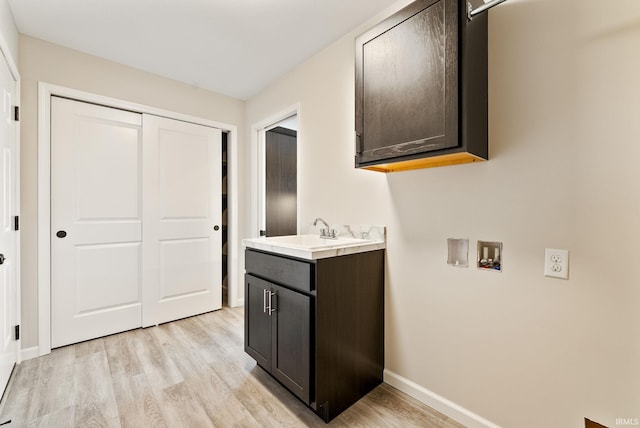 washroom with cabinets, hookup for a washing machine, light hardwood / wood-style flooring, and sink