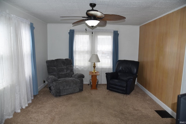 sitting room featuring light colored carpet, ceiling fan, and wooden walls