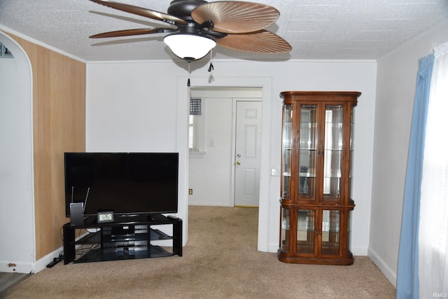 carpeted living room featuring ceiling fan and wood walls