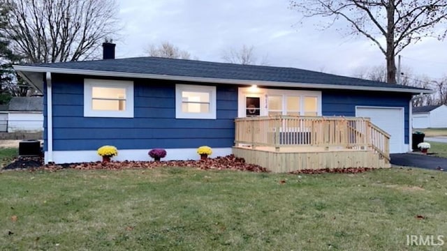 view of front facade with a garage, a deck, and a front yard