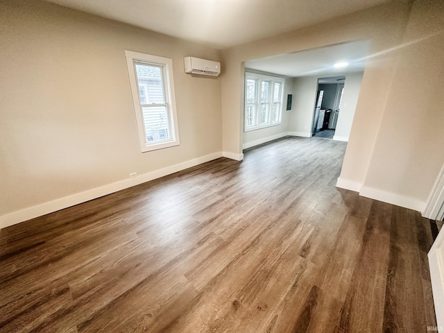 empty room featuring a wall mounted AC and hardwood / wood-style floors