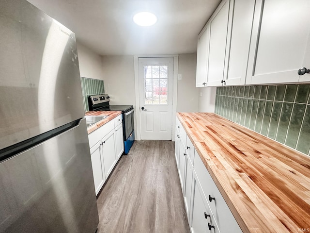 kitchen featuring wood counters, stainless steel appliances, white cabinetry, and tasteful backsplash