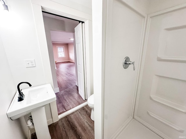 bathroom featuring hardwood / wood-style flooring, toilet, walk in shower, and sink