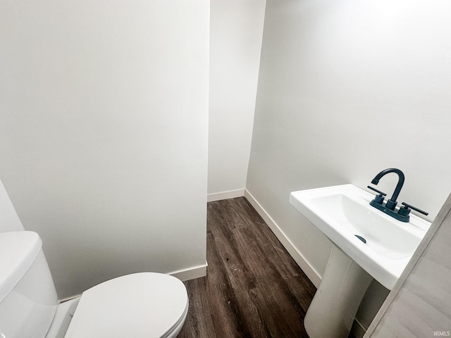 bathroom with wood-type flooring, toilet, and sink