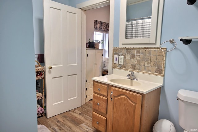 bathroom featuring hardwood / wood-style floors, decorative backsplash, toilet, and vanity